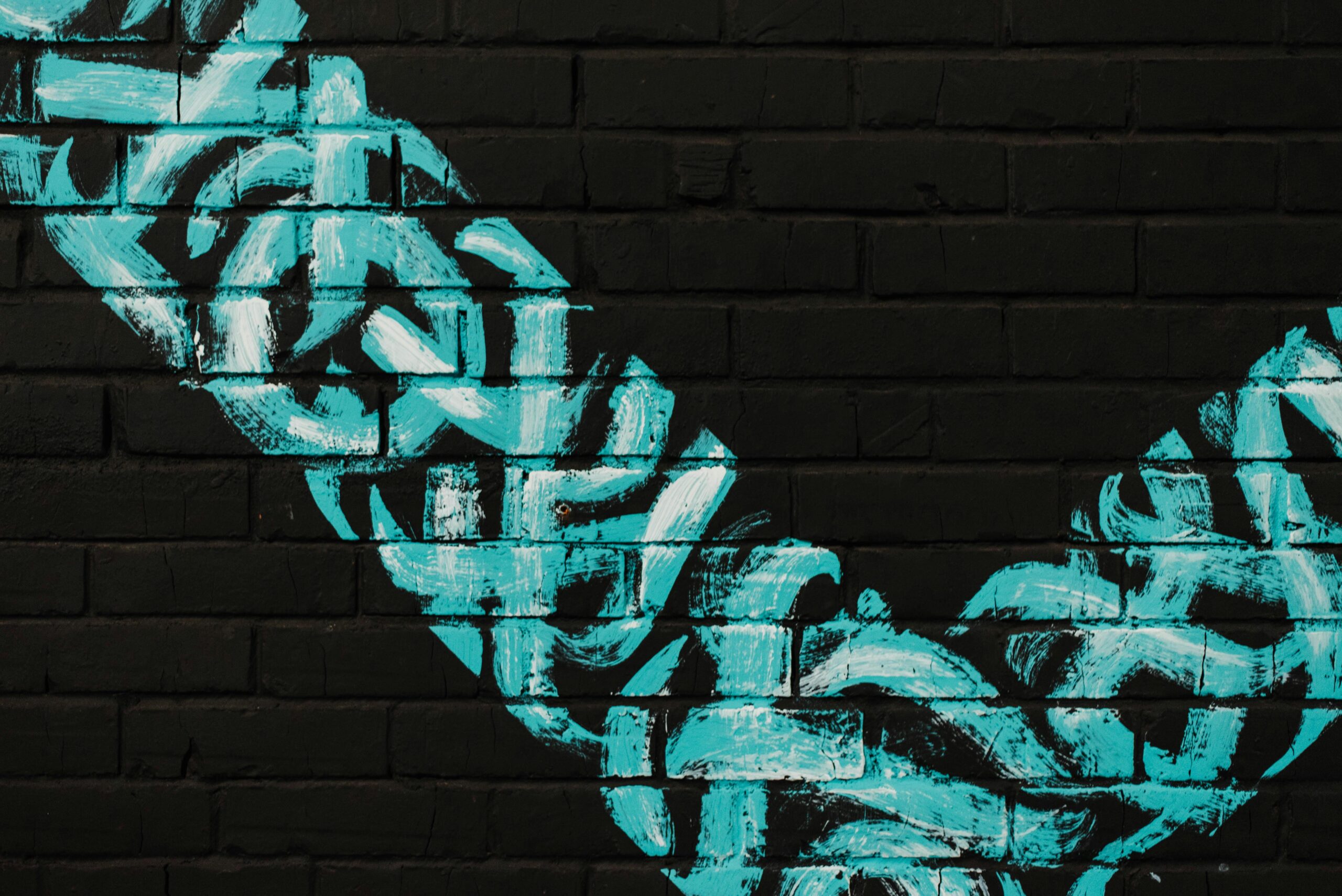 pexels-photo-3269267-3269267 Vibrant blue graffiti art on a black brick wall creating a striking contrast.